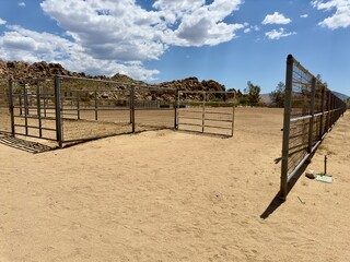 A rustic scene of a Wild West desert corral, surrounded by arid landscapes and rugged terrain, evoking the spirit of frontier life and cowboy heritage.