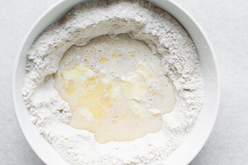 Overhead view of hot cross bun dough being mixed in a white mixing bowl, process of making hot...