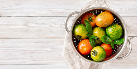 Washed various tomatoes in colander on white wooden table top view