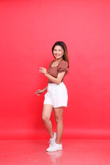 the charm of a cheerful indonesia woman in a candid dancing pose wearing a brown blouse and shorts...