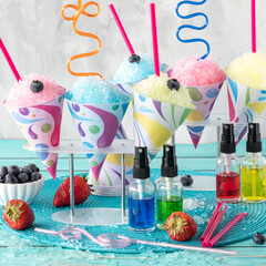 Fruit flavoured icy snow cones with different flavour syrups in front.
