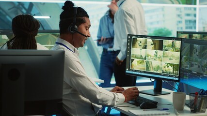Naklejka premium Indian employee communicating satellite map directions in observation room, monitoring traffic around the city via CCTV security system. Young man works with video surveillance data. Camera A.