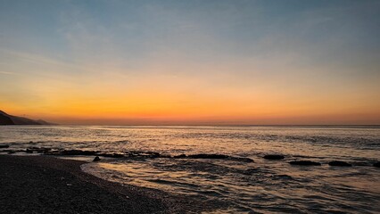 Fototapeta premium Atardecer con horizonte color naranja y oleaje en playa de la costa central de Venezuela 