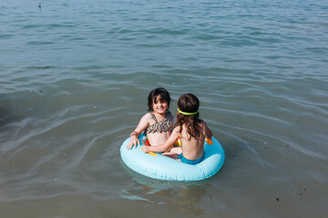 two girls swimming in the water in one inflatable ring