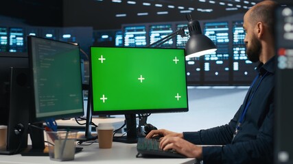 IT employee programming on green screen PC in data center housing supercomputers storing datasets....