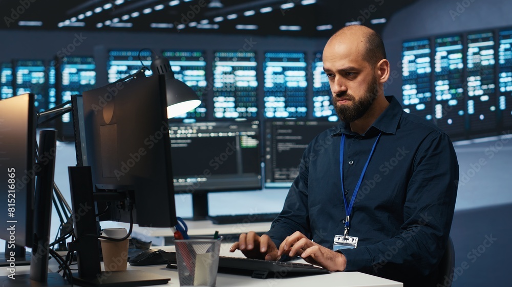Poster system operator overseeing server room, typing code on desktop pc, troubleshooting rigs. software sp