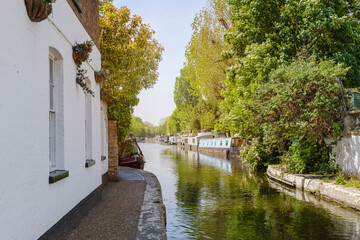 Quiet Canal Pathway with Moored Boats and Lush Greenery