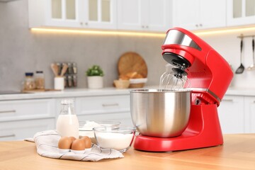 Modern red stand mixer and products on wooden table in kitchen