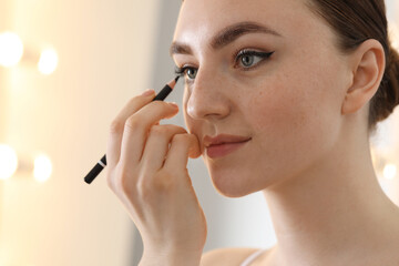 Fototapeta premium Makeup product. Woman applying black eyeliner indoors, closeup