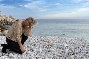 Pebble Beach Contemplation: A Woman’s Serene Moment by the Sea