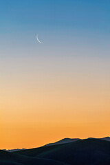 sunset on the horizon with crescent moon