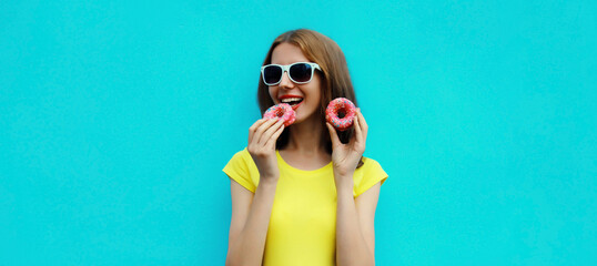 Portrait happy cheerful smiling young woman with sweet donut having fun on blue background