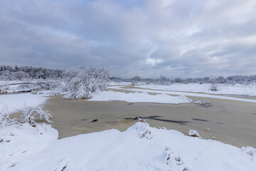 Winter landscape with frozen river and dramatic sky.