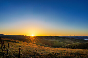 Sunrise over the hills of grass, pasture, meadow