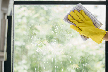 With happiness a young woman maid sprays and wipes office windows. Her housework routine emphasizes...