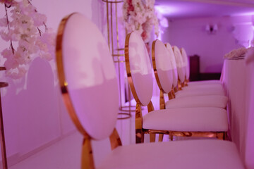 the back of the chair is gold. a row of golden metal chairs at a wedding banquet