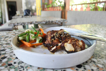 Grilled chicken breast with sliced carrots, broccoli and long beans. On a white plate ready to eat.