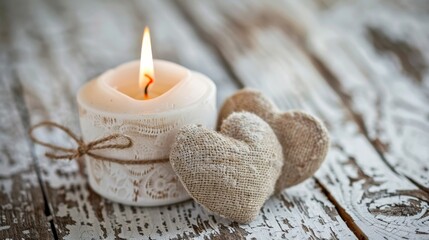 White candle, tall flame, two burlap hearts on distressed wood.