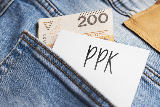  White card with a handwritten inscription "PPK", put into the pocket of blue pants jeasnow, next to Polish banknotes PLN (selective focus)