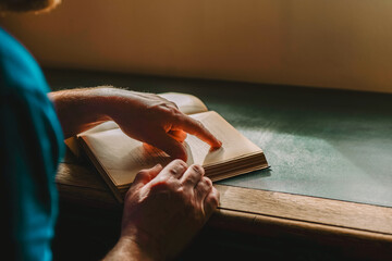 reading concept. mans hands are turning the pages of a book .man is reading a book at a desk in a...