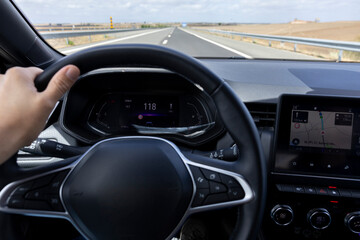 Driver view to the speedometer at 118 kmh, on a road blurred. Daylight view from inside a car of...