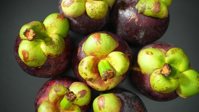 Captured in macro glory, mangosteen's allure unfolds. Its regal purple skin, crowned by verdant caps, invites admiration. Every textured contour and vivid hue whispers tales of exotic indulgence.
