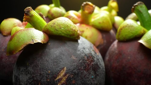 Captured in macro glory, mangosteen's allure unfolds. Its regal purple skin, crowned by verdant caps, invites admiration. Every textured contour and vivid hue whispers tales of exotic indulgence.
