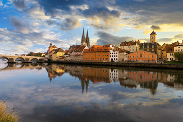 A dramatic sky with storm clouds at dusk over the skyline of the medieval old town district, the Danube River, Saint Peter's Church and Regensburg Town Hall in the Bavarian city of Regensburg, Germany