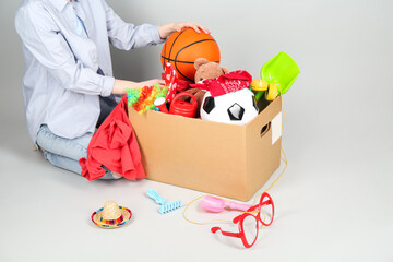 Woman with box of unwanted stuff on grey background, closeup - Powered by Adobe
