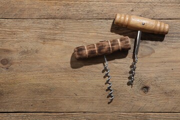 Different corkscrews on wooden table, flat lay. Space for text