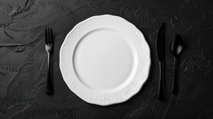 Top view of a white plate accompanied by cutlery, on a black textured background