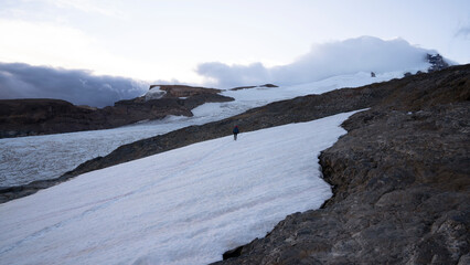 View of a hiker walking across the snow in glacier Castaño Overo, in the peak of Tronador hill in Patagonia Argentina, at sunset.	
