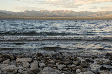 View of Nahuel Huapi lake at sunset. The rocky shore and mountains in the horizon at nightfall.
