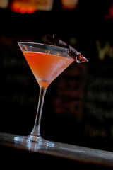 orange drink in martini glass on top of a bar