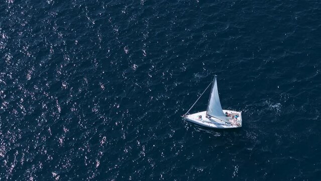 AERIAL: Flying above a luxury sailboat exploring the calm waters of the deep blue Adriatic sea. Lone sailboat makes its way through the deep blue sea on a sunny day. Fun summertime vacation activity.