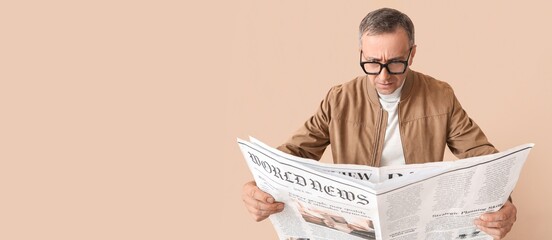 Worried mature man reading newspaper on beige background with space for text