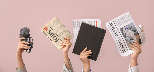 Female hands with different newspapers, notebook and microphone on color background