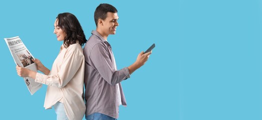 Young couple with newspaper and mobile phone on blue background with space for text