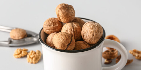 Mug of tasty walnuts on grey background