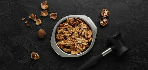 Metal bowl of tasty walnuts on black background