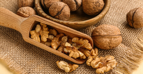 Bowl and scoop of tasty walnuts on yellow background