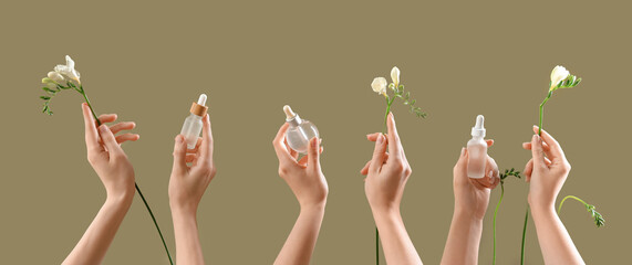 Hands holding different cosmetic products and flowers on color background