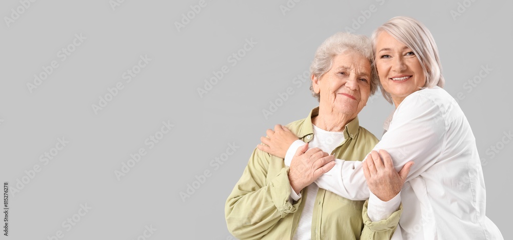 Poster Mature woman hugging her senior mother on grey background with space for text