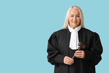 Mature female judge with gavel on blue background