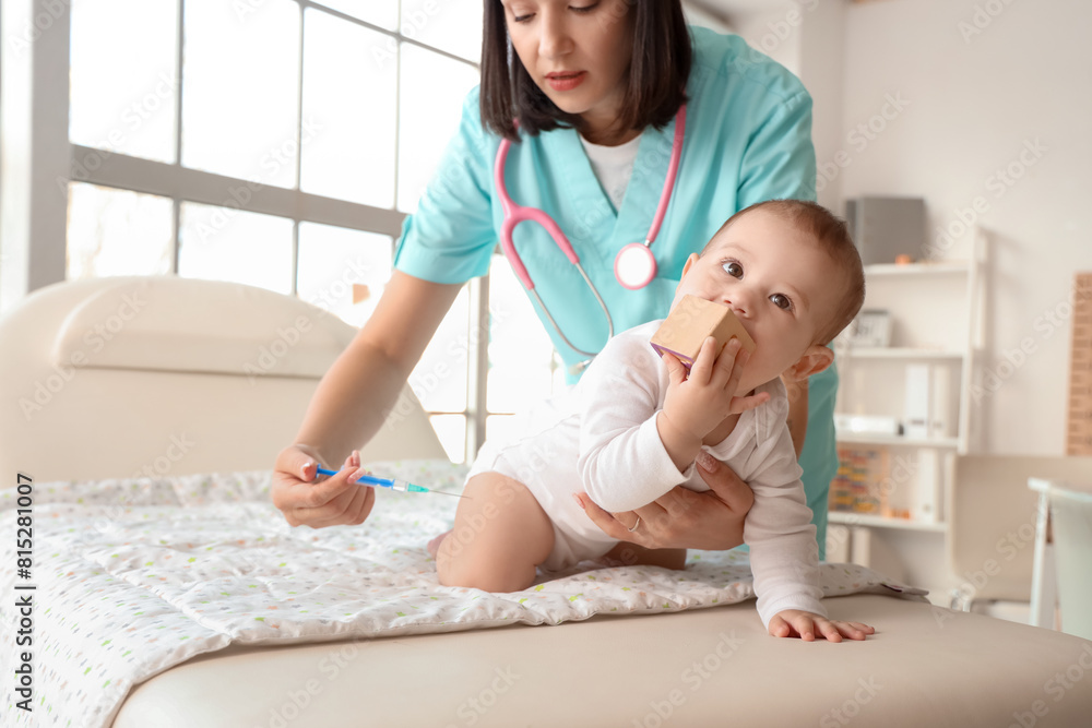 Canvas Prints Female pediatrician giving little baby injection on couch in clinic