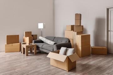 Cardboard boxes with black sofa, rolled carpet and table in living room on moving day