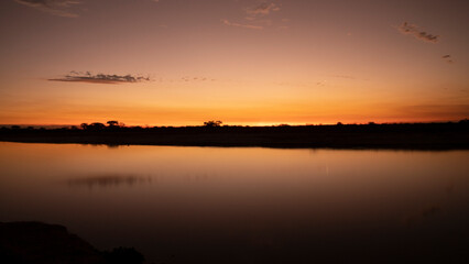 Long exposure shot of the river and coast at nightfall. Beautiful sunset sky reflection in the...
