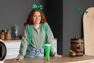 Young woman with beer in kitchen. St. Patrick's Day celebration