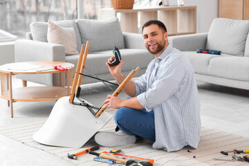 Young man with screwdriver assembling chair at home