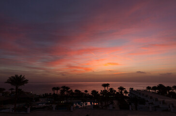 Sunrise on the sea coast. The movement of the sun and clouds across the sky. Park recreation areas of Egypt. Garden and landscape design.